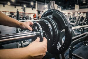 Man loading weights on bench press exercise station at the gym